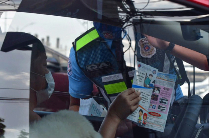 An enforcer gives a leaflet about land transportation laws to a motorist. This is in accordance with the implementation of the Child Safety in Motor Vehicles Act or Republic Act No. 11229. MARK DEMAYO/ABS-CBN NEWS