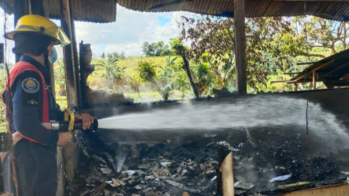 An arson investigator attempts to put out the fire that gutted the house owned by 71-year-old Rebeca Dampong in Barangay Lawaan, Dumarao, Capiz on Thursday./BFP DUMARAO