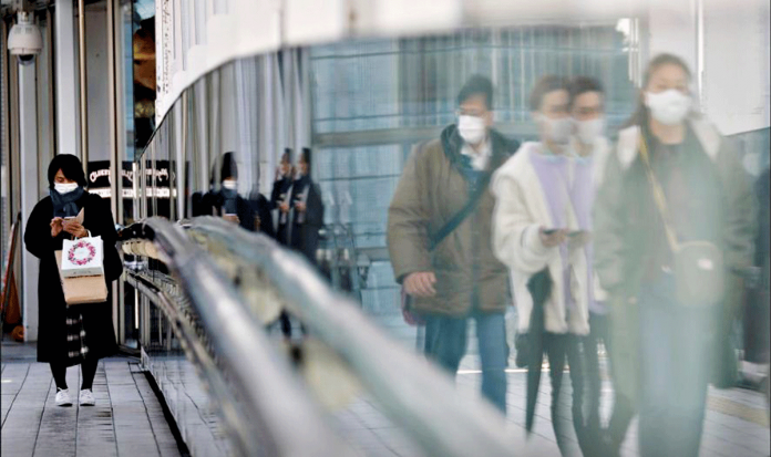 Pedestrians wearing protective masks walk on a street in Tokyo, Japan amid the coronavirus disease 2019 outbreak. .REUTERS/KIM KYUNG-HOON/FILE PHOTO