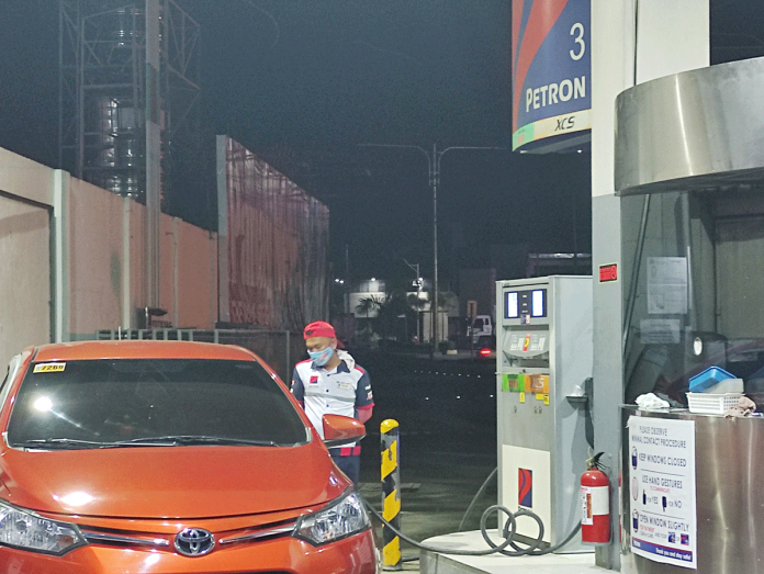 A gasoline boy fills the tank of a vehicle on Monday night. Oil firms impose again increases in their pump prices effective today. PN PHOTO