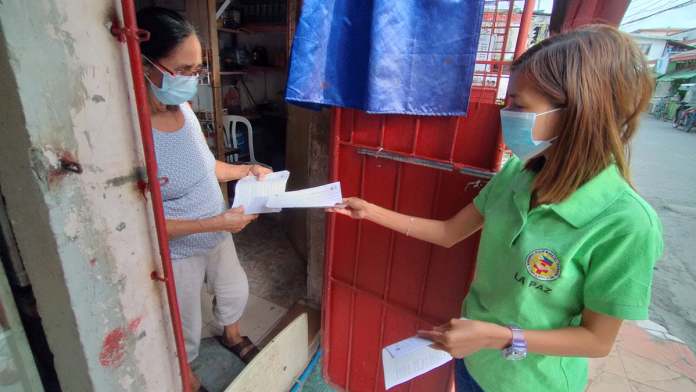 Wearing facemask, this barangay health worker hands a coronavirus vaccine consent form to a resident of Barangay San Nicolas, La Paz, Iloilo City on Feb. 19. IAN PAUL CORDERO/PN