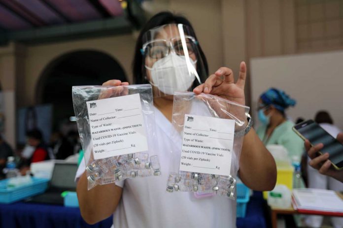 A health worker shows empty vials of CoronaVac during the vaccination of frontline healthcare workers at the University of the Philippines-Philippine General Hospital on Monday. PNA/JOEY O. RAZON