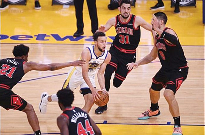 Golden State Warriors' Stephen Curry (white) runs through the defense of Chicago Bulls' Thaddeus Young (21), Tomas Satoransky (31), and Nikola Vucevic (9) during their 2020-2021 NBA game at Chase Center in San Francisco, California. JOSE CARLOS FAJARDO/BAY AREA NEWS GROUP