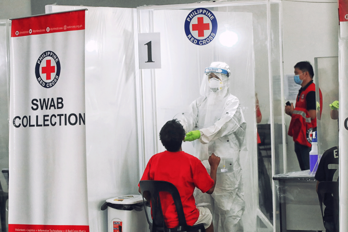 A staff from the Philippine Red Cross conducts swab test. The Philippine Health Insurance Corporation owes the Philippine Red Cross P822 million for coronavirus disease 2019 tests. IFRC