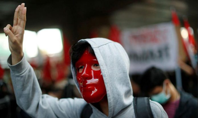 A masked anti-government protester shows the three-finger salute while marching in a protest demanding the release of arrested leaders charged with lese majeste law in Bangkok, Thailand on March 6, 2021. REUTERS/JORGE SILVA