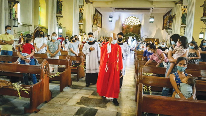 START OF HOLY WEEK. A priest blesses palm fronds at the Sta. Ana Parish Church in Molo, Iloilo City yesterday. For the second straight year, the Holy Week observance would be a lot quieter due to the restrictions brought about by the coronavirus pandemic. STA. ANA PARISH MEDIA MINISTRY