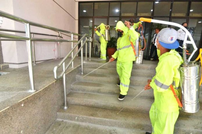 Wearing protective suits, these workers disinfect the front portion of a building as a part of precautionary measures against the coronavirus causing a pneumonia-like disease.