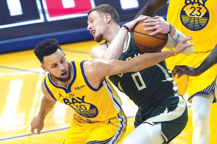 Golden State Warriors’ Stephen Curry blocks Milwaukee Bucks’ Donte DiVincenzo (0) during the first half of their 2020-2021 NBA Season game on Tuesday. JEFF CHIU/AP