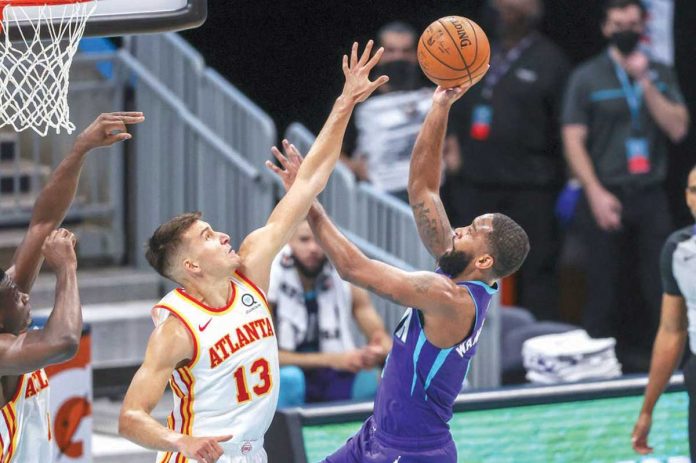 Charlotte Hornets’ Brad Wanamaker (right) shoots the ball over Atlanta Hawks’ Bogdan Bogdanovic (left) during the second quarter of their 2020-2021 NBA Season game, April 11, in Charlotte, North Carolina. AP/NELL REDMOND