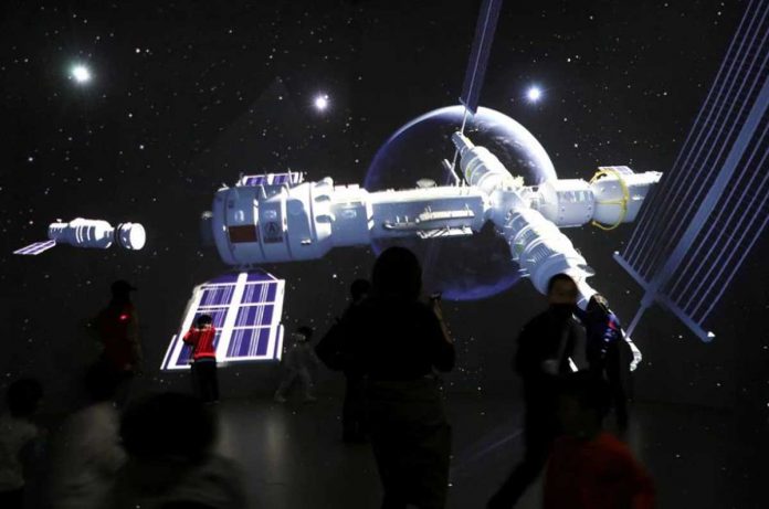 Visitors stand near a giant screen displaying the images of the Tianhe space station at an exhibition featuring the development of China's space exploration on the country's Space Day at China Science and Technology Museum in Beijing. REUTERS/TINGSHU WANG