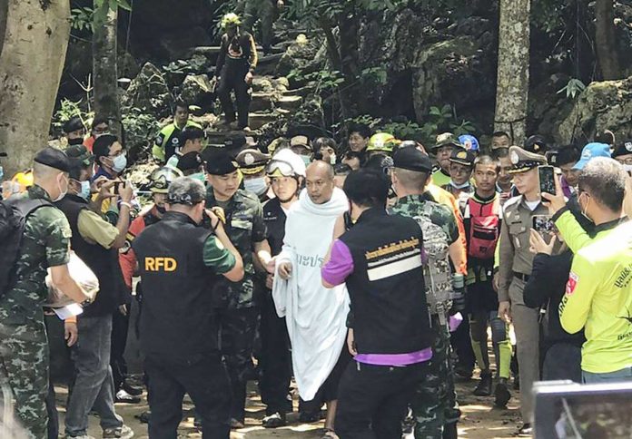 Rescuers help Phra Manas (center) walk out from Tham Phra Sai Ngam cave in Thailand on Wednesday. The 46-year-old monk was trapped inside a cave for four days. AP