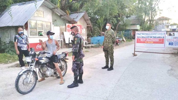 Policemen stop a motorist at a checkpoint in Barangay Manocmanoc, Boracay Island. Zones 1 and 7 of the village have been on surgical lockdown since April 1 due to rising cases of coronavirus disease 2019.