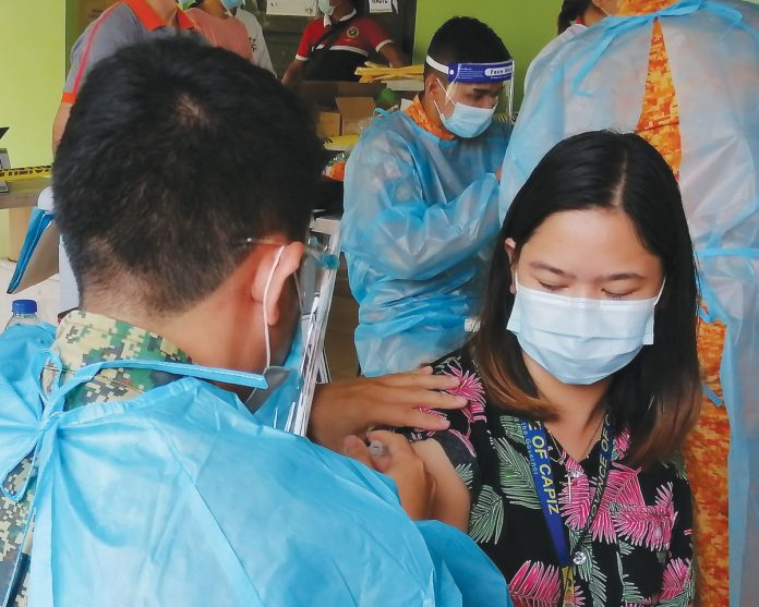 An employee of the provincial government of Capiz gets a “vaccine shot” during a vaccination simulation at the Villareal Stadium in Roxas City.