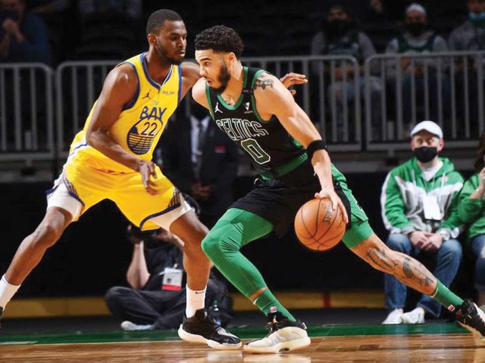 Boston Celtics' Jayson Tatum (right) backs down the defense of Golden State Warriors' Andrew Wiggins (left) during their basketball match in the 2020-2021 NBA Season, Saturday, in Boston, Massachusetts. BRYAN BABINEAU/GETTY IMAGES