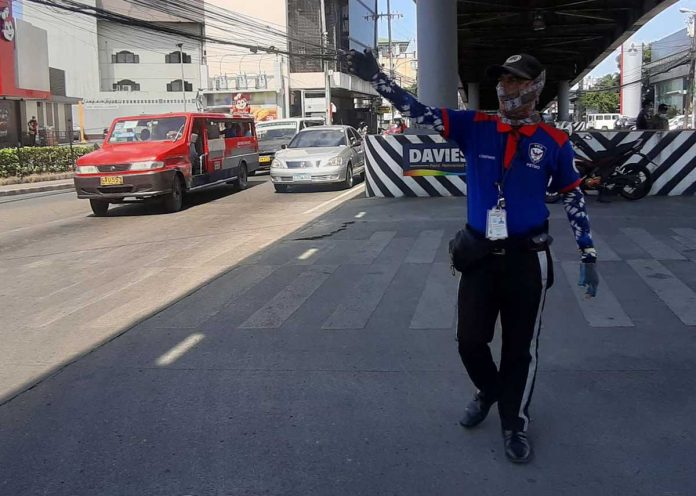 A traffic enforcer directs the flow of vehicles and pedestrians in Molo, Iloilo City. The city will now fully compensate traffic auxiliaries for their 26 days of duty every month. However, some of them will be retrenched. JAPHET FAJARDO/PN