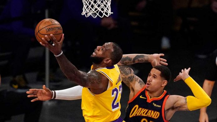 Los Angeles Lakers forward LeBron James (left) shoots past Golden State Warriors forward Juan Toscano-Anderson (right) during the first half of their basketball game in California on Wednesday. MARK TERRILL