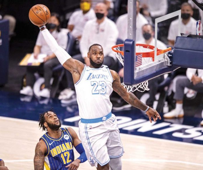 Los Angeles Lakers forward LeBron James (23) goes for a slam dunk as Indiana Pacers center Oshae Brissett looks on during their NBA basketball game on Saturday. DOUG MCSCHOOLER / ASSOCIATED PRESS