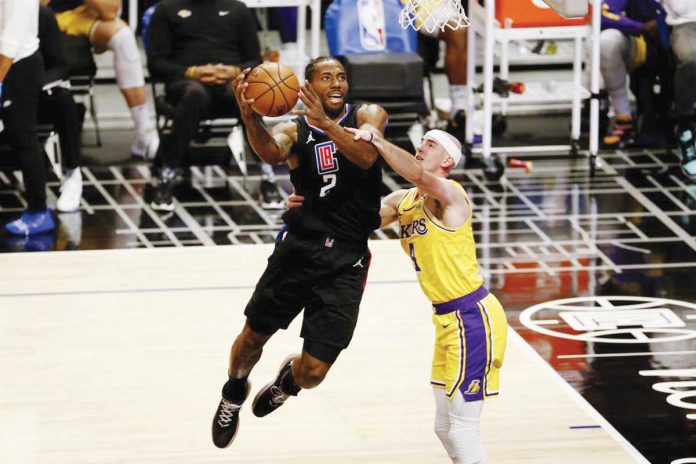 Los Angeles Clippers’ Kawhi Leonard (2) drives to the basket and is fouled by Alex Caruso (4) of Los Angeles Lakers during the second half of their basketball game on Thursday. AP PHOTO/RINGO H.W. CHIU