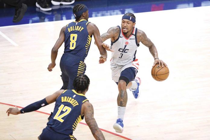 Washington Wizards' Bradley Beal (3) dribbles the ball while Indiana Pacers’ Justin Holiday (8) and Oshae Brissett (12) defend during the first half of their basketball match in the Eastern Conference’s play-in game held in Washington, May 20, 2021. AP PHOTO/NICK WASS