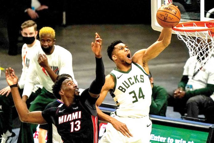 Giannis Antetokounmpo (34) shoots past Miami Heat’s defender Bam Adebayo (13) to score for Milwaukee Bucks during Game 3 of NBA’s Eastern Conference first-round playoffs on Thursday at the American Airlines Arena in Florida. MORRY GASH/AP