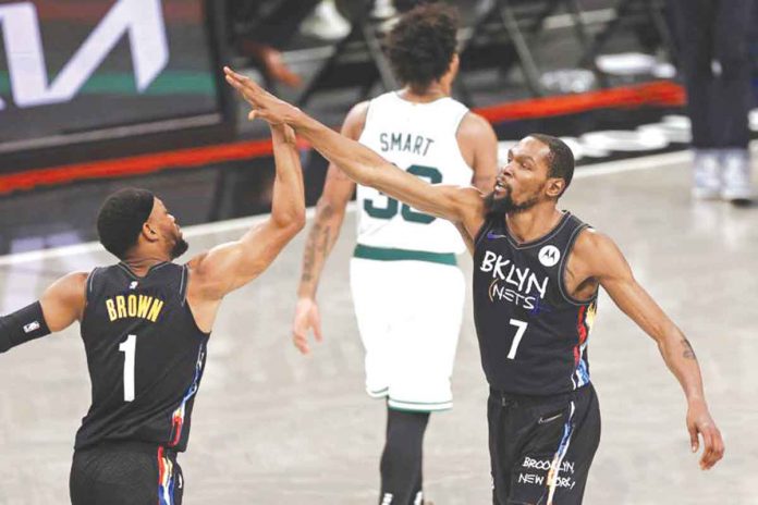 Brooklyn Nets’ Kevin Durant (7) high-fives Bruce Brown while Boston Celtics’ Marcus Smart walks off the court during the second half of Game 5 of the NBA Eastern Conference first-round playoffs series on Tuesday. AP/ADAM HUNGER