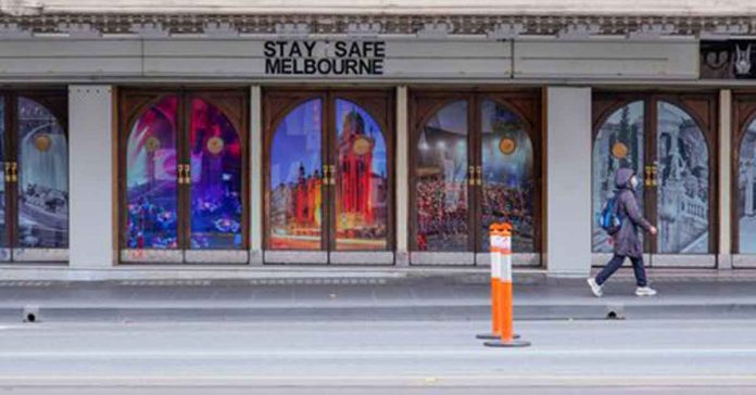 A woman walks past a "Stay Safe Melbourne" sign on a mostly-empty city street on the first day of a seven-day lockdown as the state of Victoria in Australia looks to curb the spread of COVID-19. REUTERS/SANDRA SANDERS