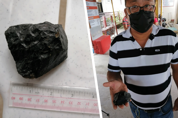 DOMINIQUE GABRIEL BAÑAGA/PN School principal Mario Amaca holds a meteorite recovered on the grounds of Negros Occidental High School.
