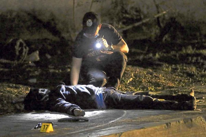 WAR ON DRUGS. A police investigator inspects the body of a suspected victim of extrajudicial killing. INQUIRER PHOTO