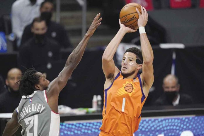 Phoenix Suns’ Devin Booker (right) shoots over Los Angeles Clippers’ Patrick Beverley (left) during the first half of Game 4 of their Western Conference Finals on Saturday. AP PHOTO/MARK J. TERRILL