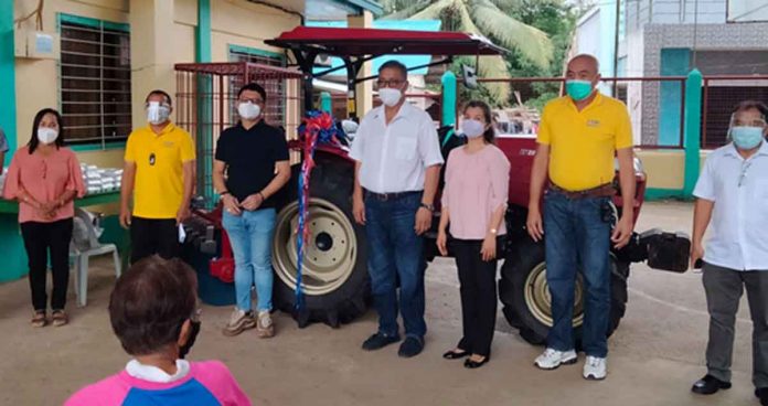 DOLE-6 regional director Cyril Ticao and CFO officer-in-charge-head Amalia Judicpa (fourth and fifth from left) lead in the turnover of the farm tractor (in the background) to Fernadez Farm Association in Capiz. DOLE-6