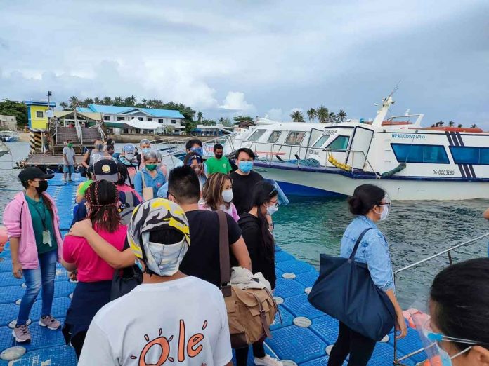 The local government of Malay, Aklan recommends rapid antigen tests for workers returning to Boracay Island to help workplaces there reopen and ensure tourists’ safety. Photo shows people queuing to board a boat bound for Boracay at the jetty port in Caticlan, Malay, Aklan.