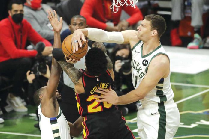 Milwaukee Bucks' Brook Lopez (right) blocks the shot attempt of Atlanta Hawks' John Collins (center) during the first half of Game 5 of their Eastern Conference finals. The Bucks scored 123-112 to seize a 3-2 lead in the series over the Hawks. AP/AARON GASH