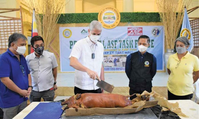 Governor Eugenio Jose Lacson leads the ceremonial slicing of a lechon during the second anniversary celebration of the Provincial African Swine Fever Task Force at the Capitol Social Hall in Bacolod City on Monday. One of the reasons Negros Occidental remains ASF-Free, according to the governor, is the creation of the ASF Task Force. PIO-NEGROS OCCIDENTAL