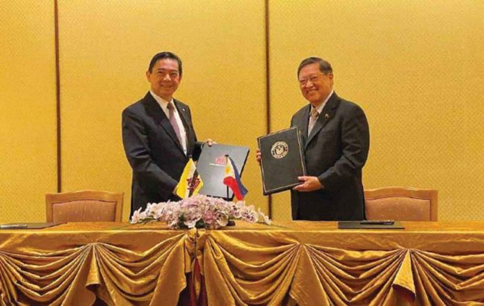 Department of Finance secretary Carlos Dominguez (right) of the Philippines and Yang Berhormat Dato Seri Setia Dr. Awang Haji Mohd Amin Liew bin Abdullah (left), minister at the Prime Minister’s Office and Minister of Finance and Economy II of Brunei Darussalam, hold their copies of the double taxation agreement. VIA ABS-CBN NEWS