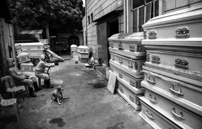 Workers in protective suits, used due to the COVID-19 coronavirus outbreak, wait outside a crematorium facility in Manila. MARIA TAN/AFP VIA INQUIRER