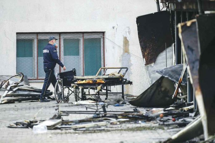 A police officer walks past burned hospital equipment on the site of a destroyed field hospital following a fire in Tetovo, North Macedonia. AP/VISAR KRYEZIU