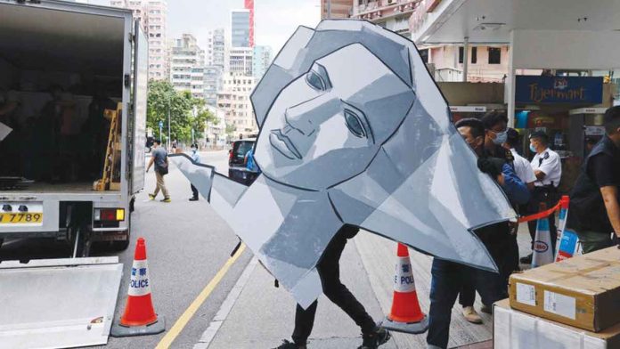 The Hong Kong police remove a paper model of the Goddess of Democracy from the Tiananmen Square museum. REUTERS