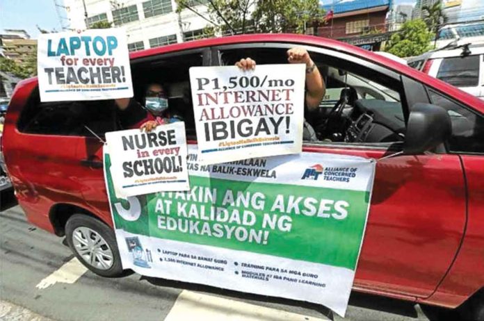 JUST DEMANDS . Teachers hold a drive-by protest at the central office of the Department of Education in Pasig City. INQUIRER FILE PHOTO