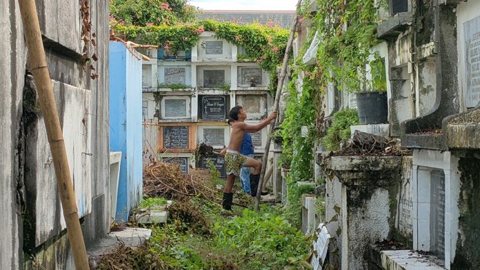 Policemen will be roving around cemeteries to ensure public compliance with the minimum health standards and other “Undas” measures being implemented by local government units. Photo shows people clearing this portion of the Molo public cemetery in Iloilo City. PANAY NEWS PHOTO