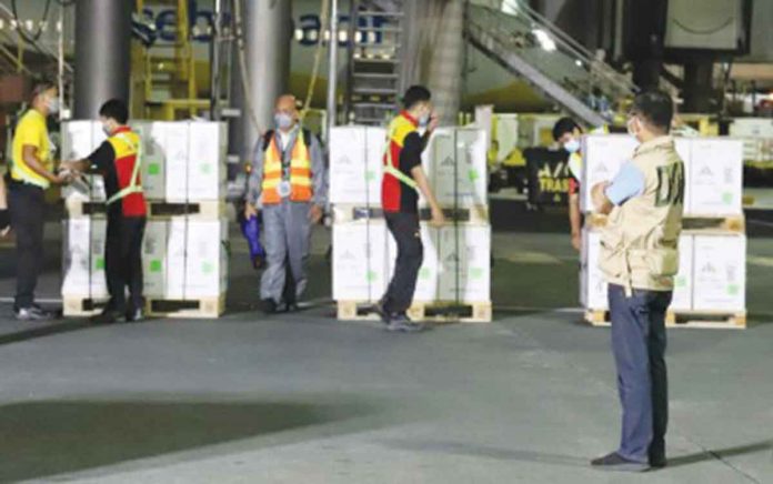 Department of Health (DOH) officer Jaime Laya (right) monitors the checking of the newly shipped boxes containing Pfizer Covid-19 vaccine at the NAIA Terminal 3 in Pasay City on Wednesday night (Dec. 8, 2021). The latest vaccine delivery is expected to further boost the second leg of the national vaccination days on December 15 to 17.