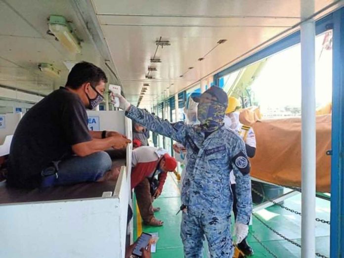 A Philippine Coast Guard personnel check the body temperature of this Boracay Island-bound traveler in a motorboat. PHILIPPINE COAST GUARD PHOTO