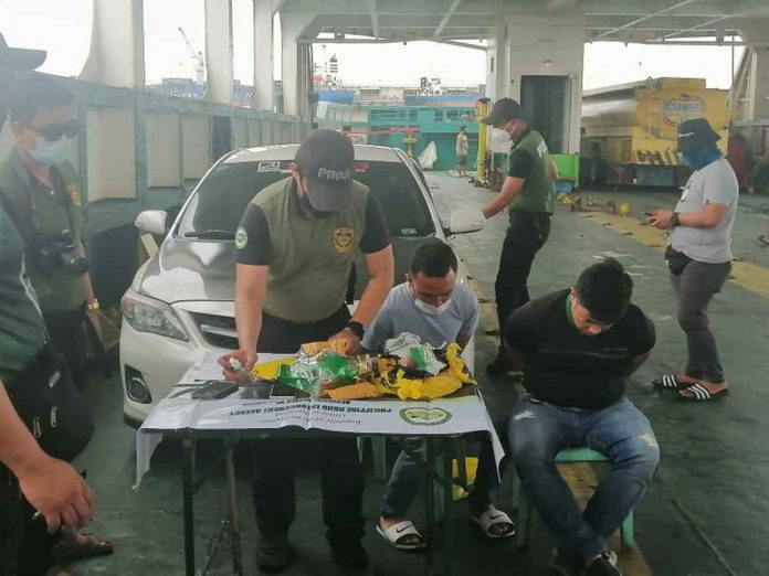 BUSTED. An operative of the Philippine Drug Enforcement Agency checks the items seized from two suspects (seated) arrest at the BREDCO Port in Bacolod City. From Metro Manila, the suspects traveled via roll-on/roll-off vessel from Batangas to Caticlan (Malay, Aklan) then traveled by land to Dumangas, Iloilo from where they boarded another roro vessel going to Bacolod City. PCG-NEGROS OCCIDENTAL PHOTO