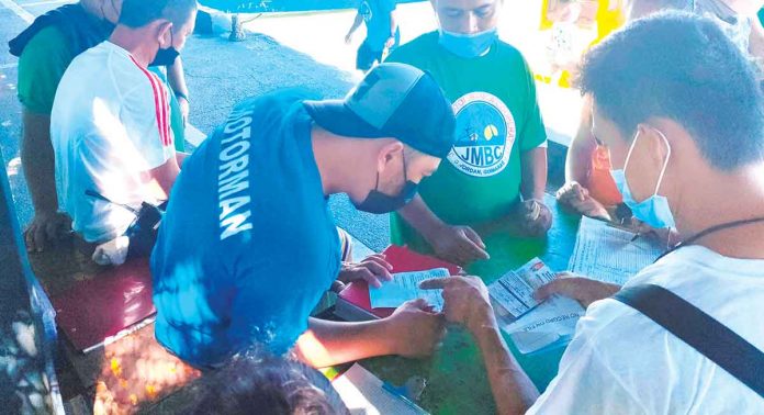 AUTHENTIC OR FAKE? An inspector at the Parola wharf in Iloilo City scrutinizes the COVID-19 vaccination card of a man who intends to travel to nearby Guimaras Island. Aside from the vaccination card, the man is also required to present a valid identification card and an outbound pass. PN PHOTO