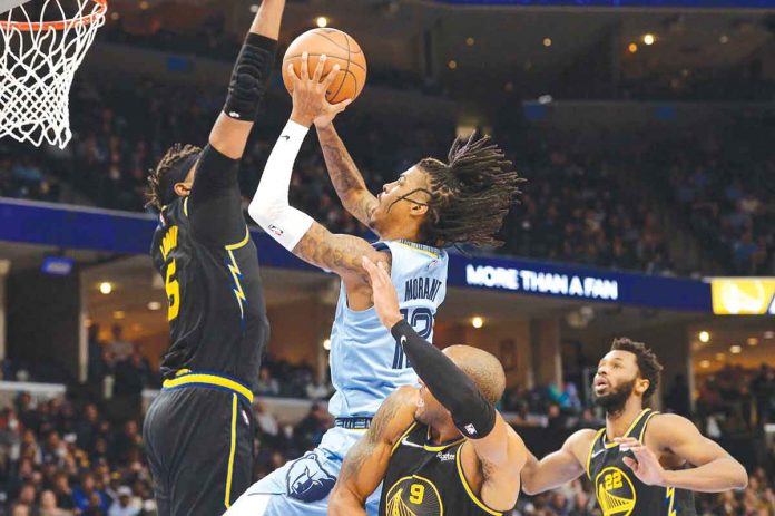 Memphis Grizzlies’ Ja Morant attacks the defense of Golden State Warriors’ Kevon Looney for a layup. AP PHOTO