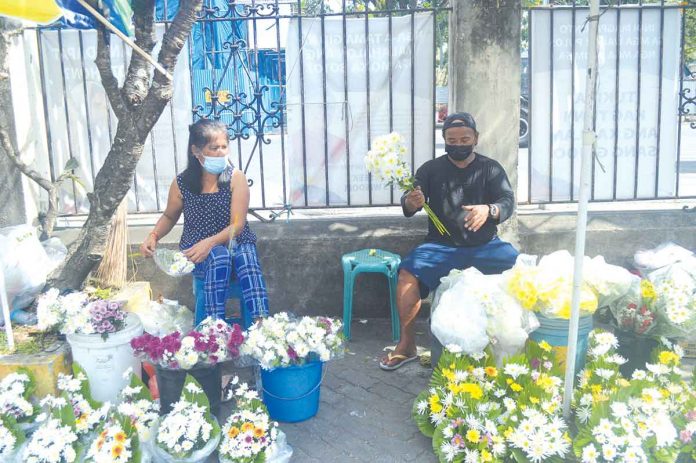 Vendors selling flowers, candles and religious articles wait for buyers outside the Jaro Metropolitan Cathedral in Iloilo City. Restrictions on the movement of people due to the coronavirus pandemic have reduced their volume of customers. PN PHOTOS