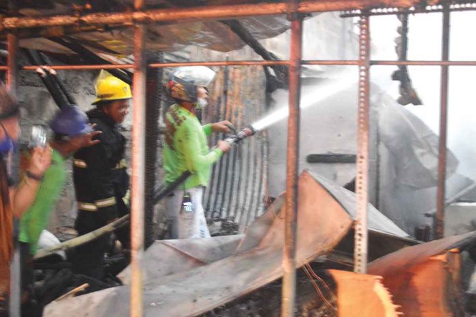 FIRE ALERT. Firefighters spray with water these houses that fire gutted in Barangay Old Airport, Mandurriao, Iloilo City late afternoon to early evening on March 11, 2022. Sixty-six houses were destroyed and 107 families were displaced. They temporarily sought shelter at the Mandurriao Elementary School. PN PHOTOS