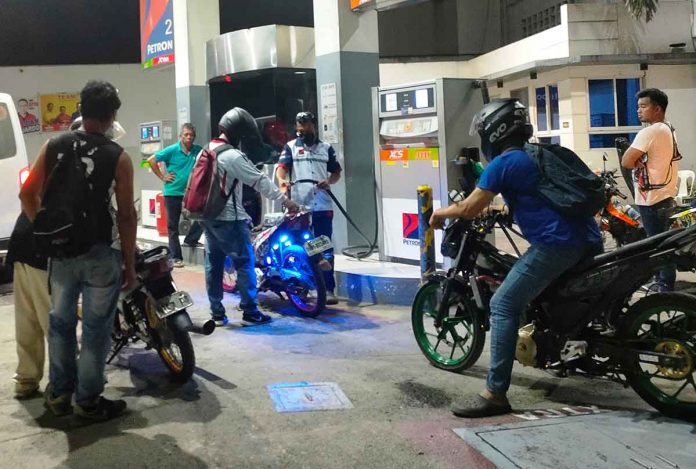 Motorcycle riders wait for their turn to refuel at a gas station in Pavia, Iloilo on Friday night, hours before another round of fuel price increase takes effect. PN PHOTO