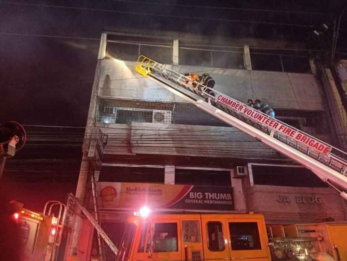 Firefighters use a long ladder to get to the upper floors of this fire-hit building in Bacolod City on Monday night, April 25. Smoke can be seen billowing from the building. BFP-BACOLOD PHOTO