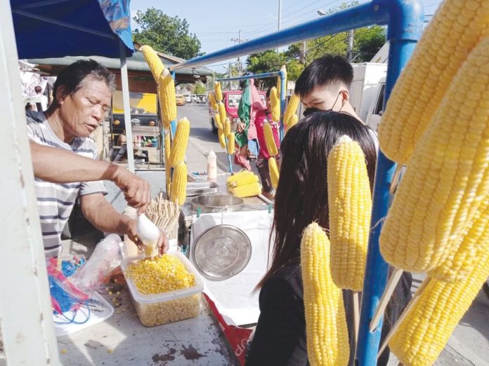 A vendor sells corn in Barangay Baluarte, Molo, Iloilo City. Thanks to the easing of pandemic restrictions, he could now resume his humble business. In a statement, the country’s economic managers say many jobs and livelihood were restored “by shifting to a more endemic mindset, accelerating vaccination, and implementing granular lockdowns that only targeted the areas of highest risk while allowing the majority of our people to work and earn a living.” PHOTO BY IME SORNITO