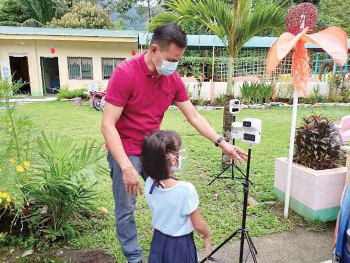 At Laserna Integrated School in Nabas, Aklan, a pupil undergoes a body temperature check. The school has resumed in-person classes.